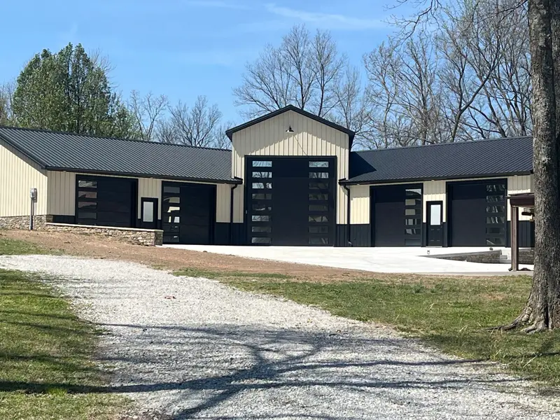 Black and tan steel building with black full-view glass overhead doors