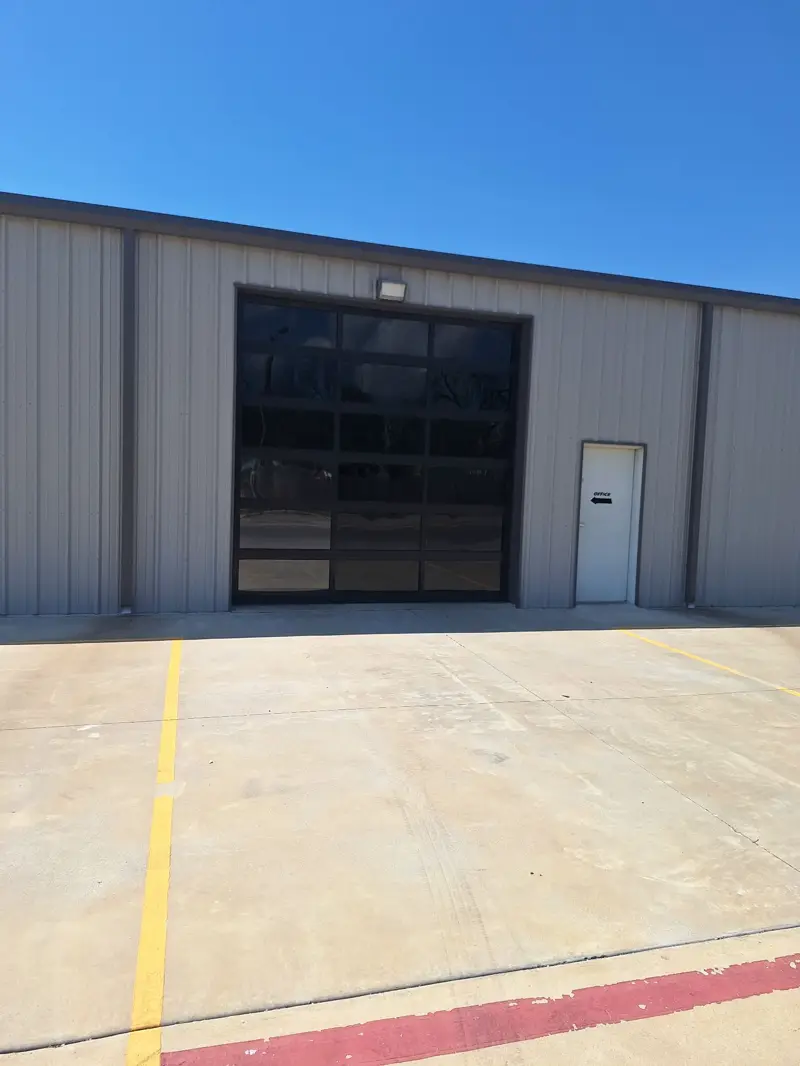 Black aluminum full-view commercial door on a grey steel building