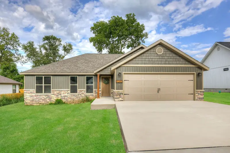 Stone and siding ranch home with a tan two-car garage door