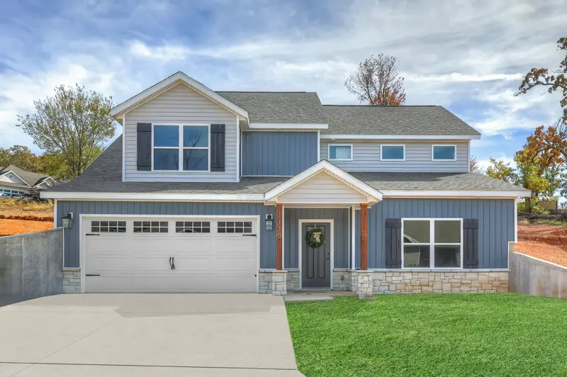 Two-story blue home with a white two-car garage door with windows